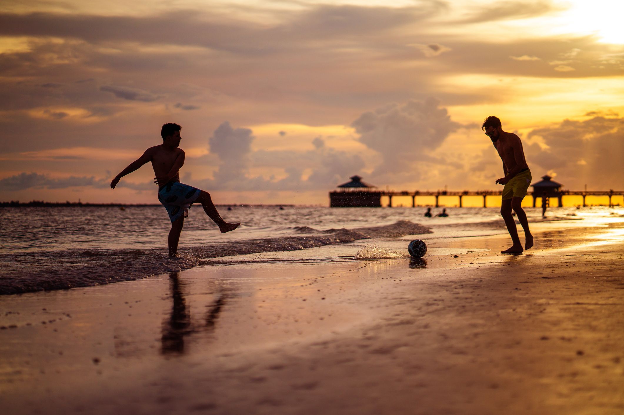 Two men play soccer on the beach in Fort Myers.